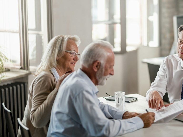 Älteres Paar und Berater besprechen Unterlagen in einem hellen, modernen Raum.